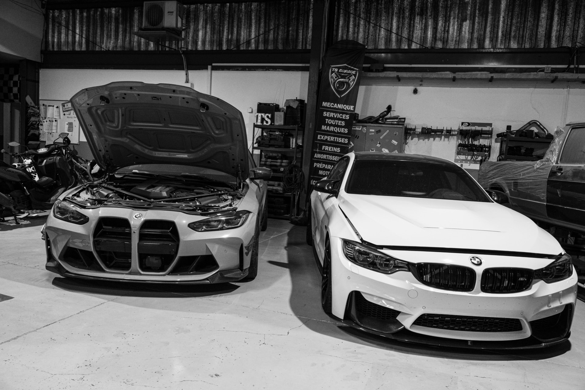Deux voitures dans l'atelier TS Garage, photographiées en noir et blanc